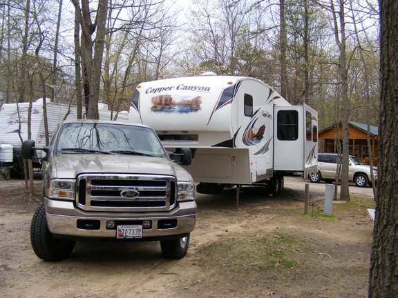 Our tan Ford F-250 is parked
           in front of the Copper Canyon trailer. Leafless trees
           surround the area.