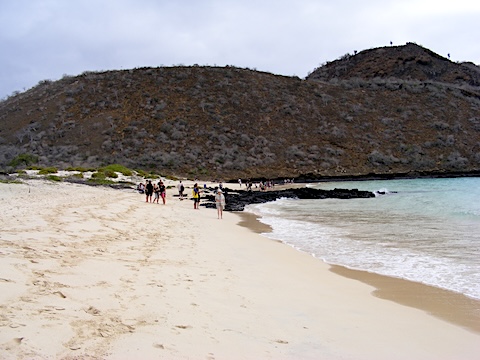 The beach is a broad stretch of sand with 
            a hill of volcanic rock behind it