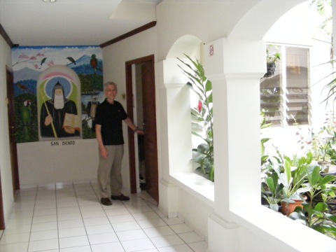 Al standing at the door to our room, with the 
                  mural of San Benito on one side and the little
                  garden courtyard on the other