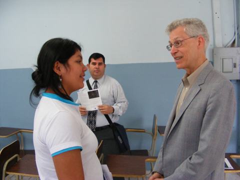 Al talks with a student in the lecture hall.
                   A faculty member waits in the background.