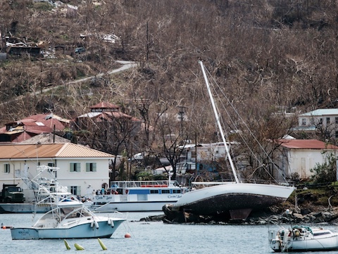 Seen from the water level, a brown hillside with houses and a yacht on the shore 