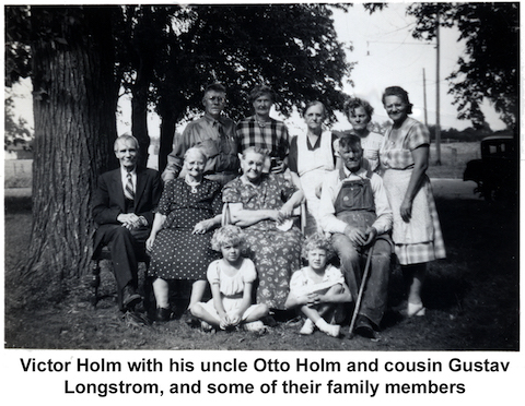 The people at the reunion are outside, with some sitting in a 
           row of chairs, others standing behind them, and two young girls
           on the ground in front.