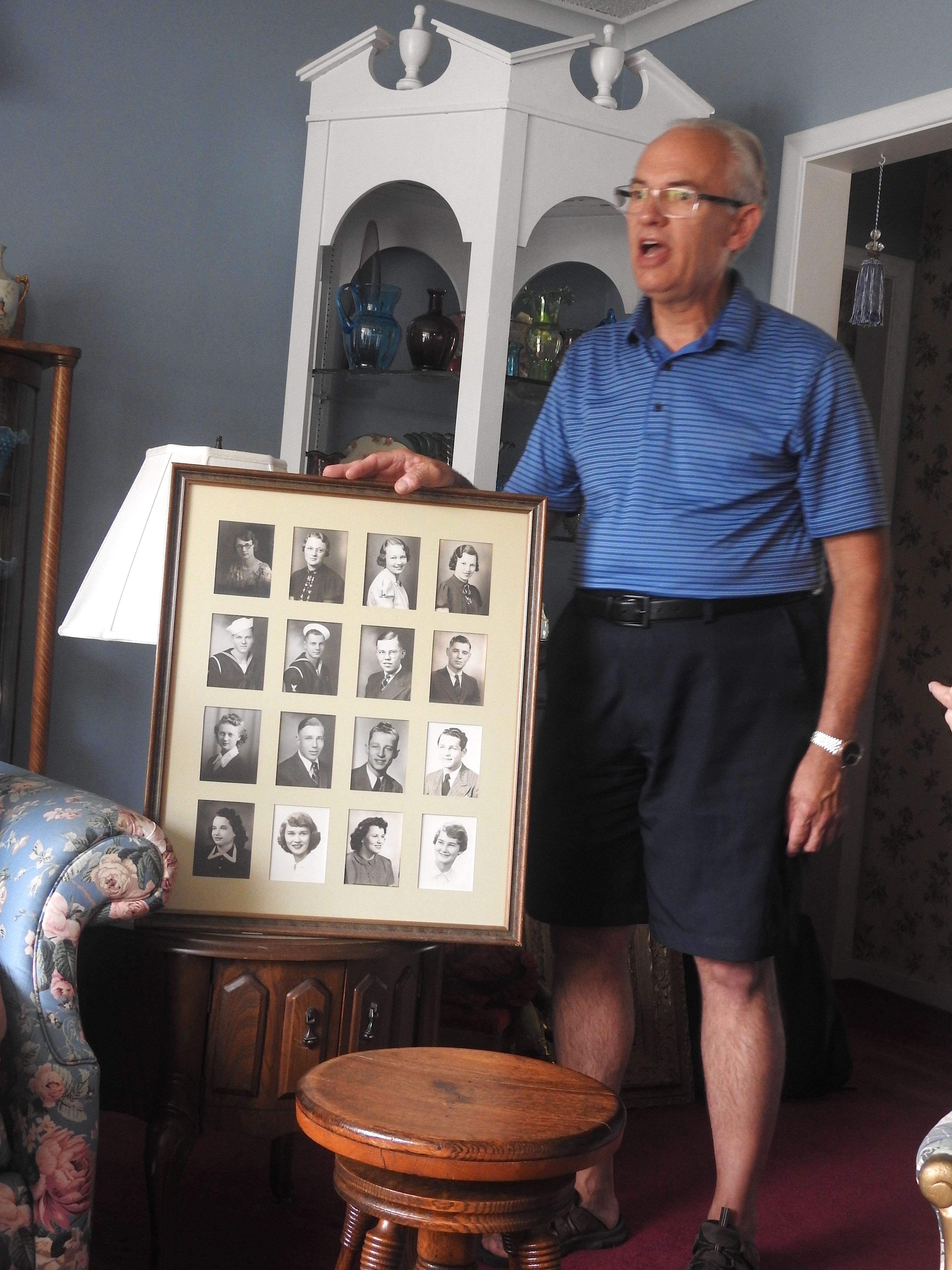 Mark is holding a frame withh 16 photos of the children