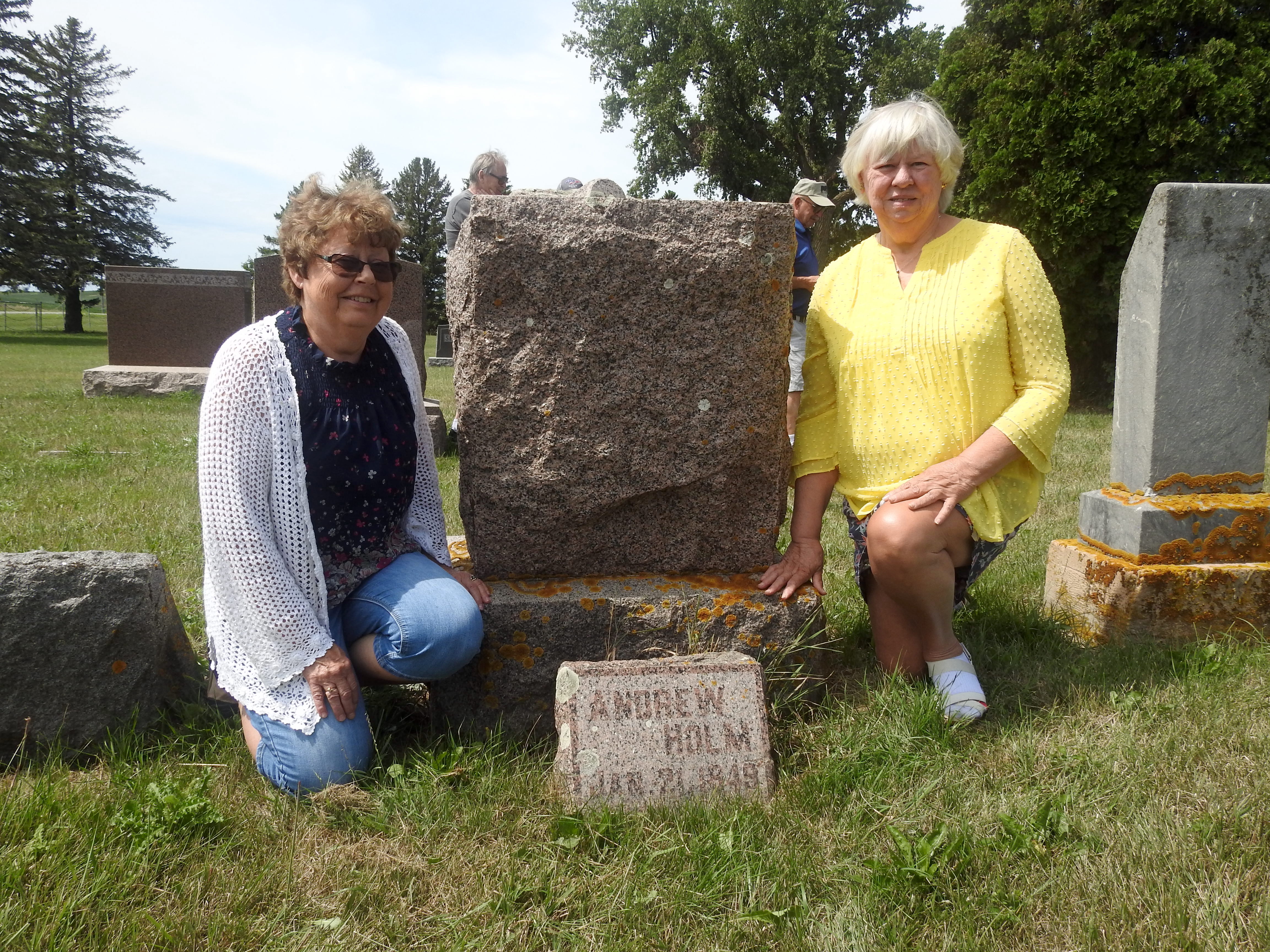 Norma Campbell and Eunice Helgeson kneeling by Andrew Holm’s marker