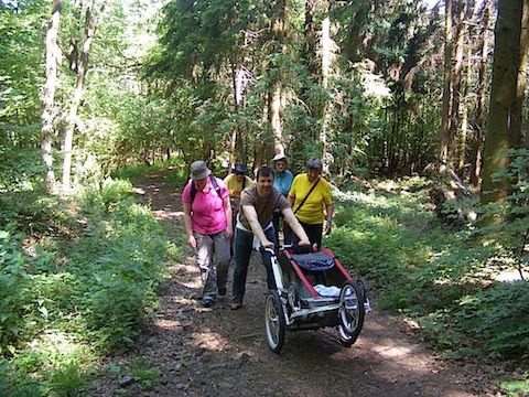 Holgar pushes the stoller/trailer containing Felix up the 
              rugged forest trail. The other members of our group are in
              a bunch behind him.