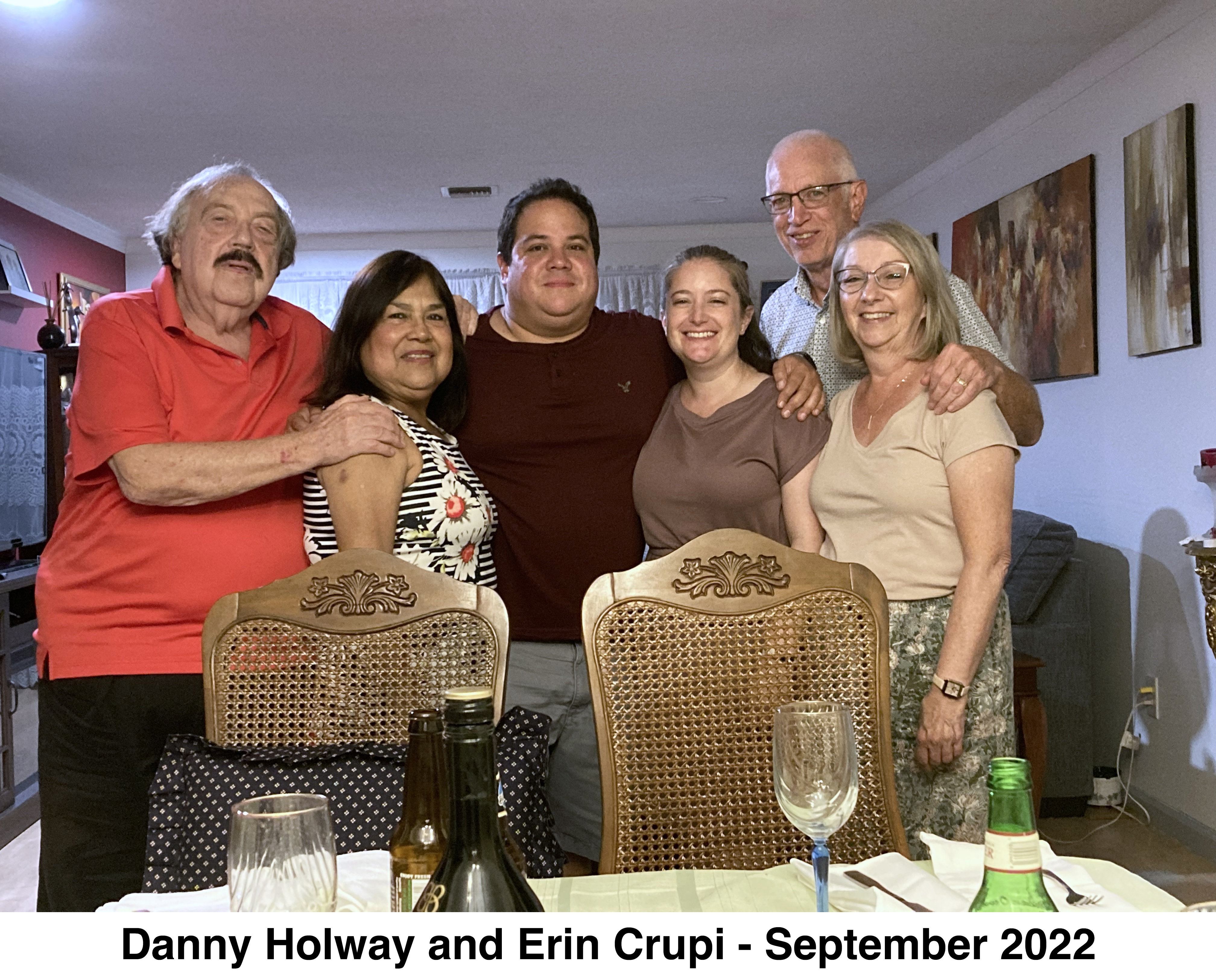Danny and his fiancee are in the middle, His parents are to 
           the left and her parents are on the right. They are behind a table.