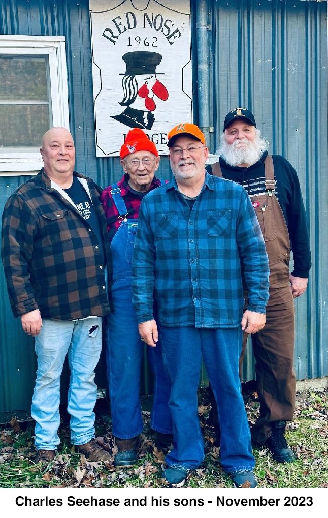 The four men are standing in front of a wall that has a sign reading
       “Red Nose Lodge 1962ž 