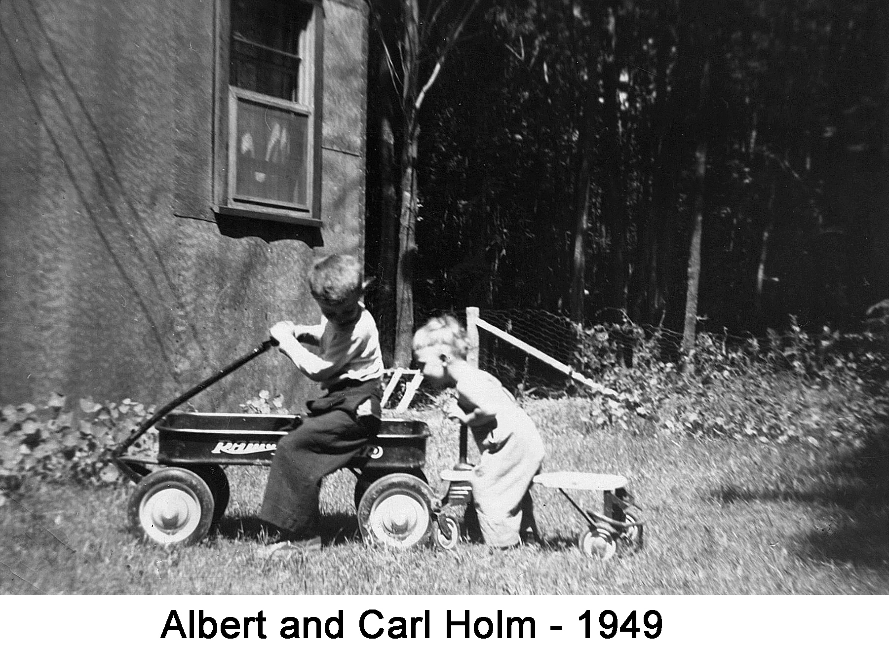 Albert is sitting in the wagon looking back at Carl who is butting the 
       wagon with his scooter. 