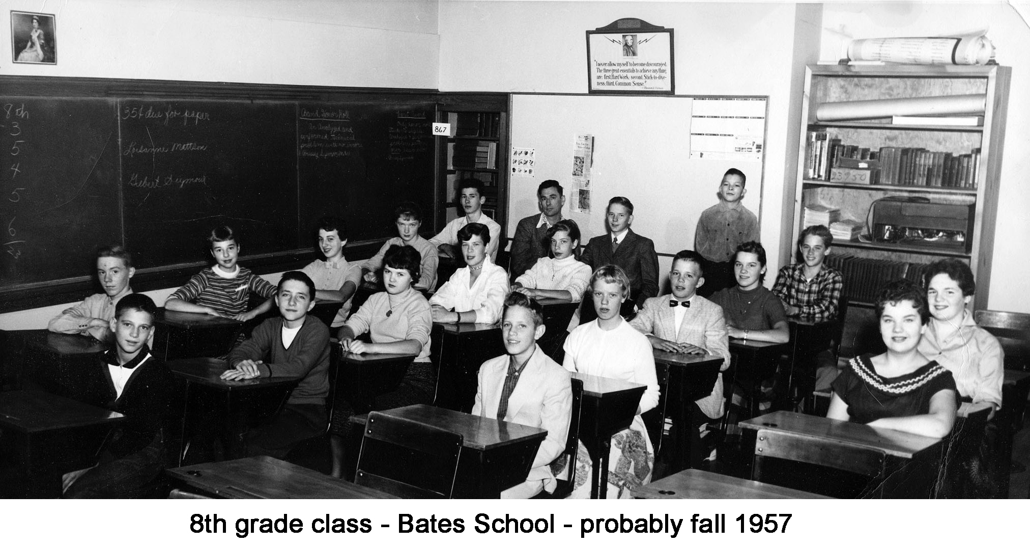 All but one of the students and the teacher are sitting in their desks.