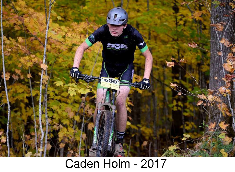 He is among trees on his bike, coming toward the camera with 
        mud splatters on his legs and a determined look on his face