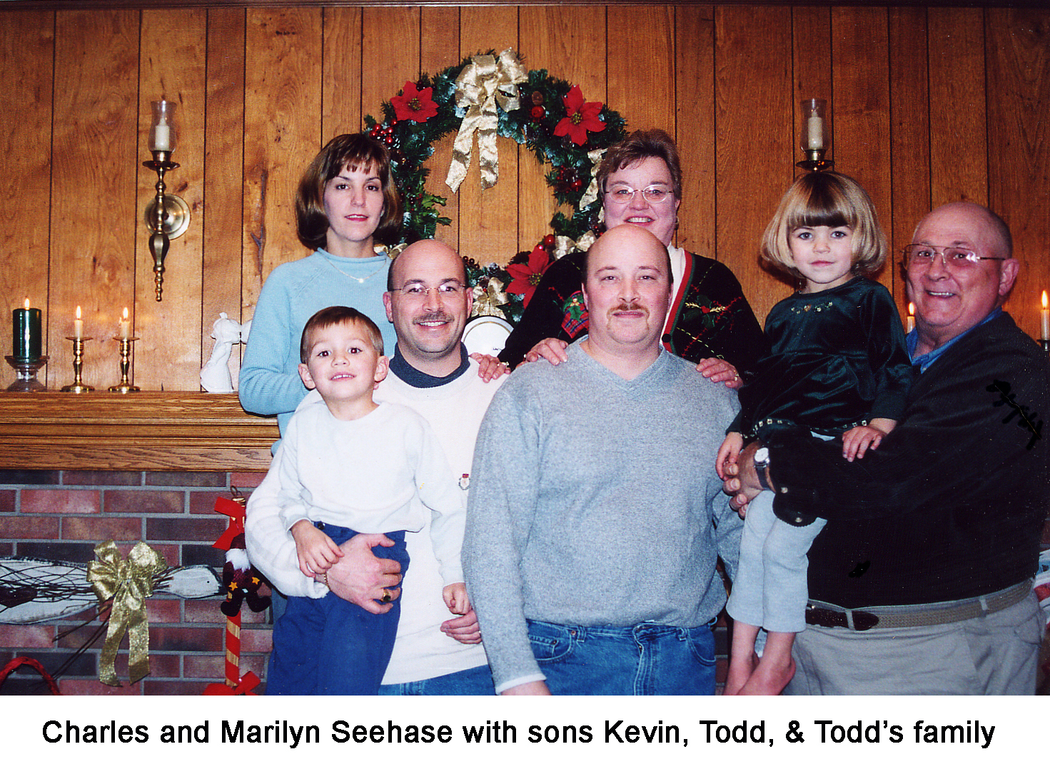 Charles and Marilyn Seehase with their family posed in front of the fireplace and a large wreath