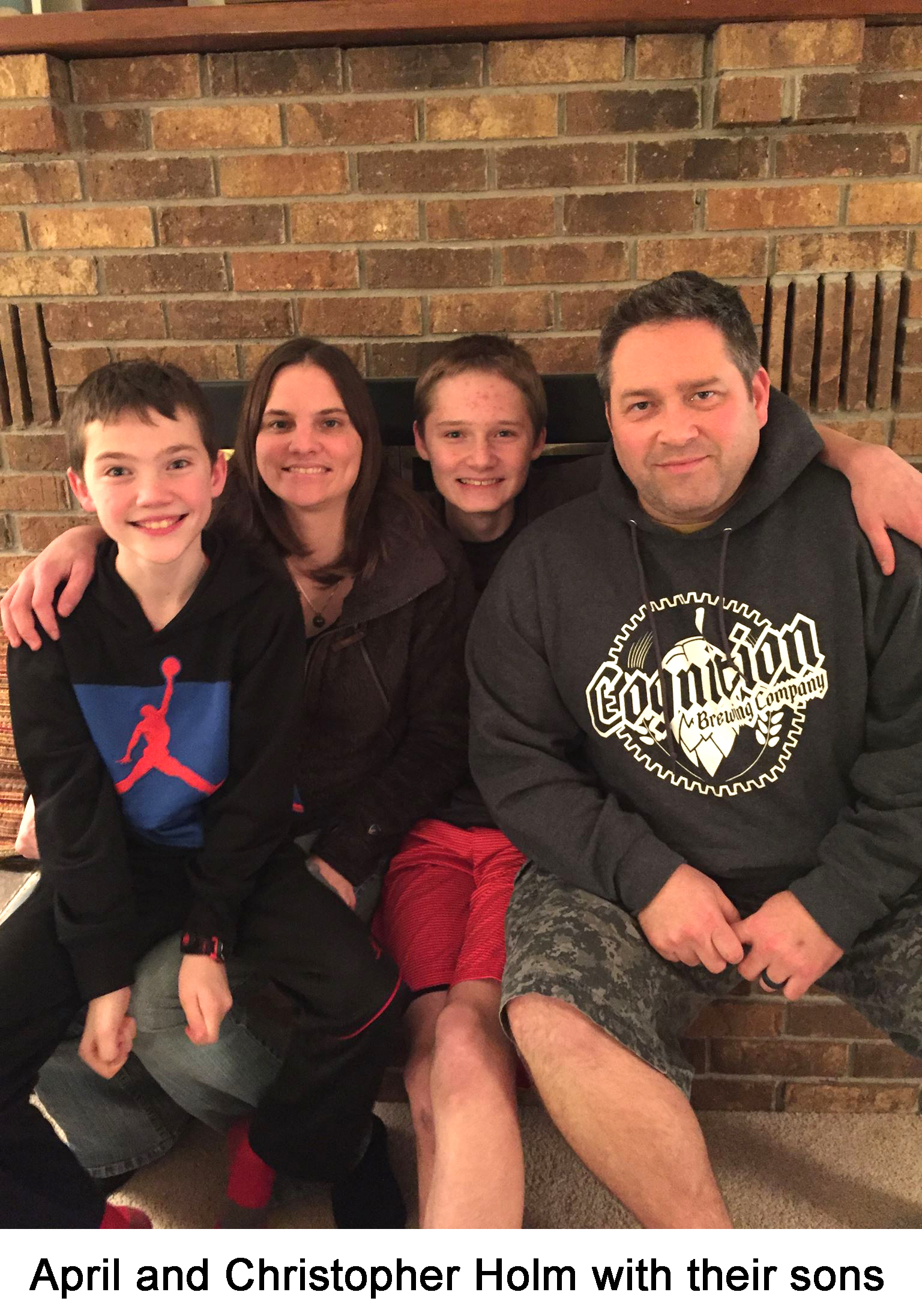 The family is sitting in front of a brick fireplace