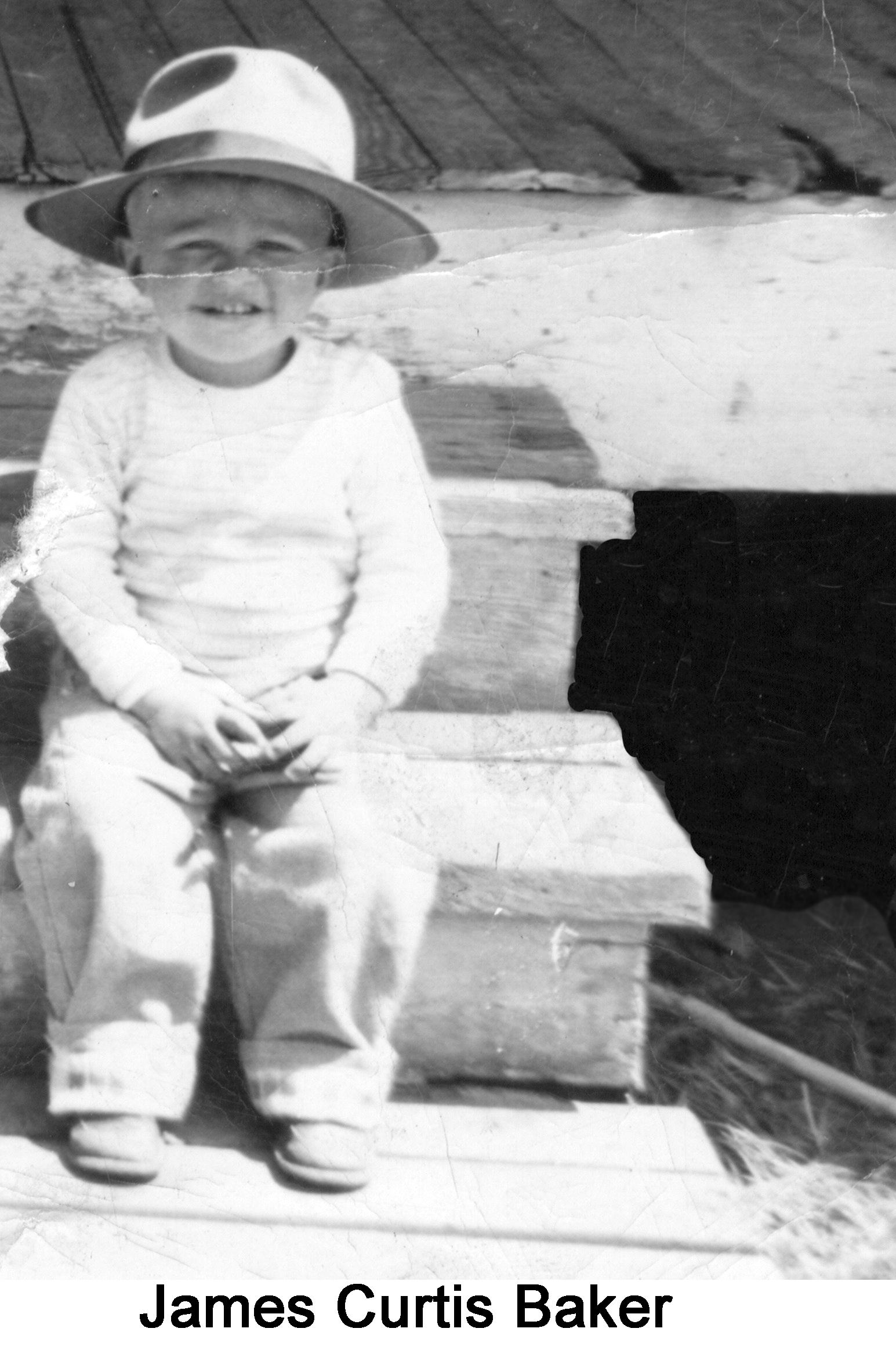 Curt is sitting on steps, wearing an oversized, brmmed hat.