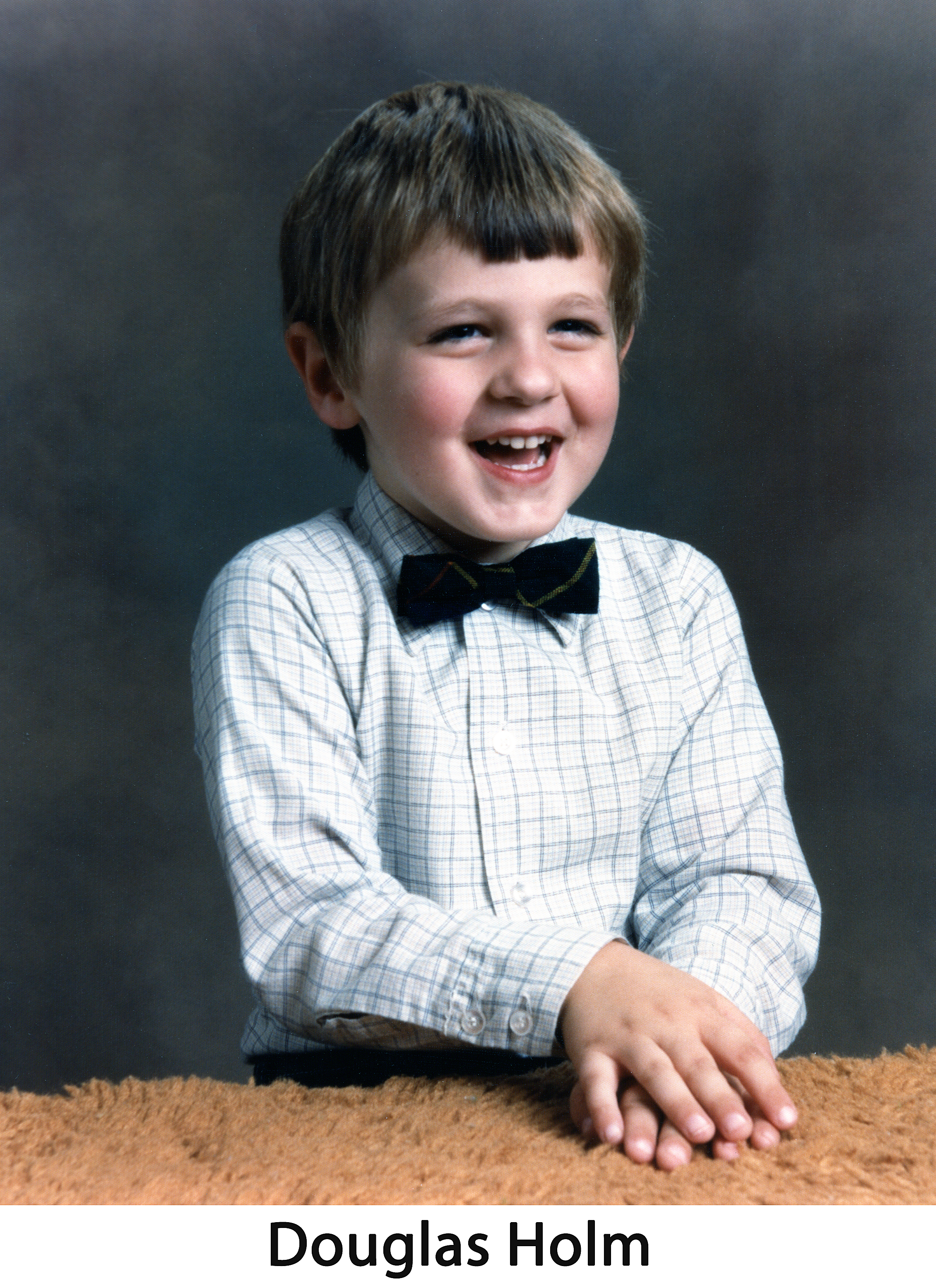 Douglas is laughing and wearing a bowtie in front of a dark background