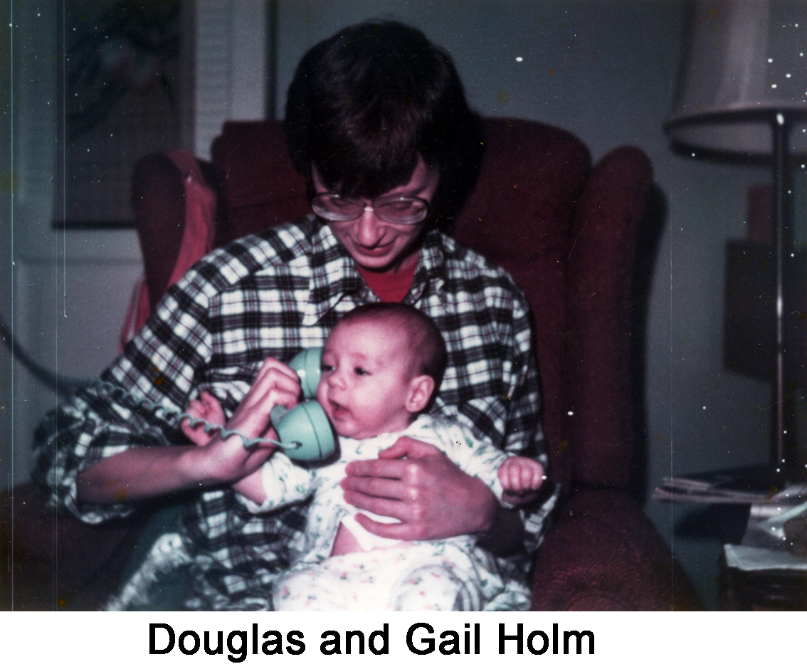 Douglas is sitting on Gail's lap and his head is turned toward the phone Gail
        is holding to his right hear. He appears to be engaged in a conversation.