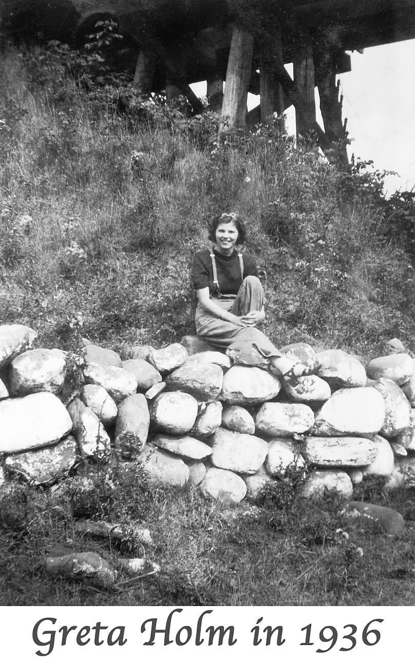 Greta Holm at age 16 sitting on a boulder wall with a wooden bridge behind her