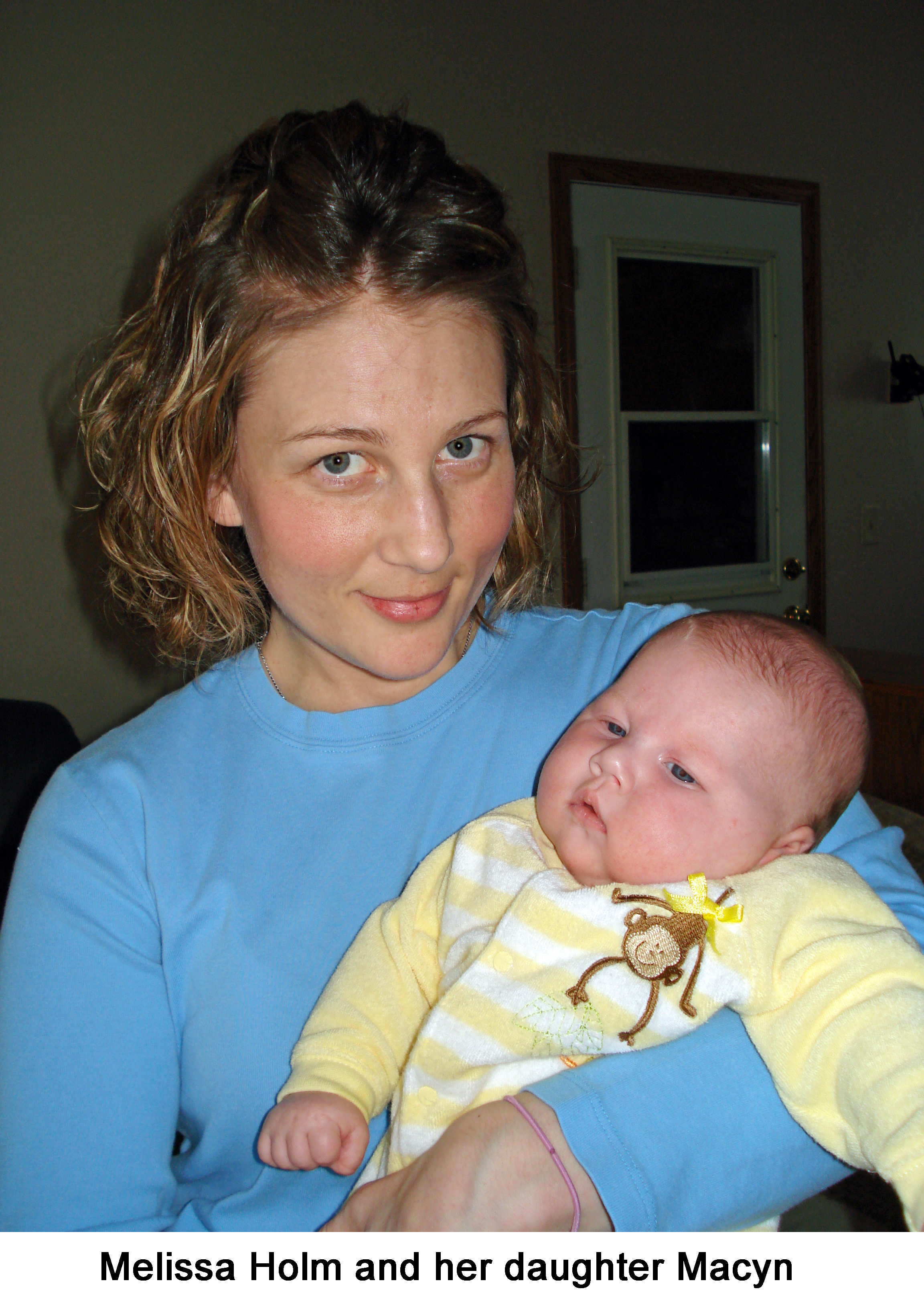 Melissa is looking at the camera and holding a drowsy looking Macyn