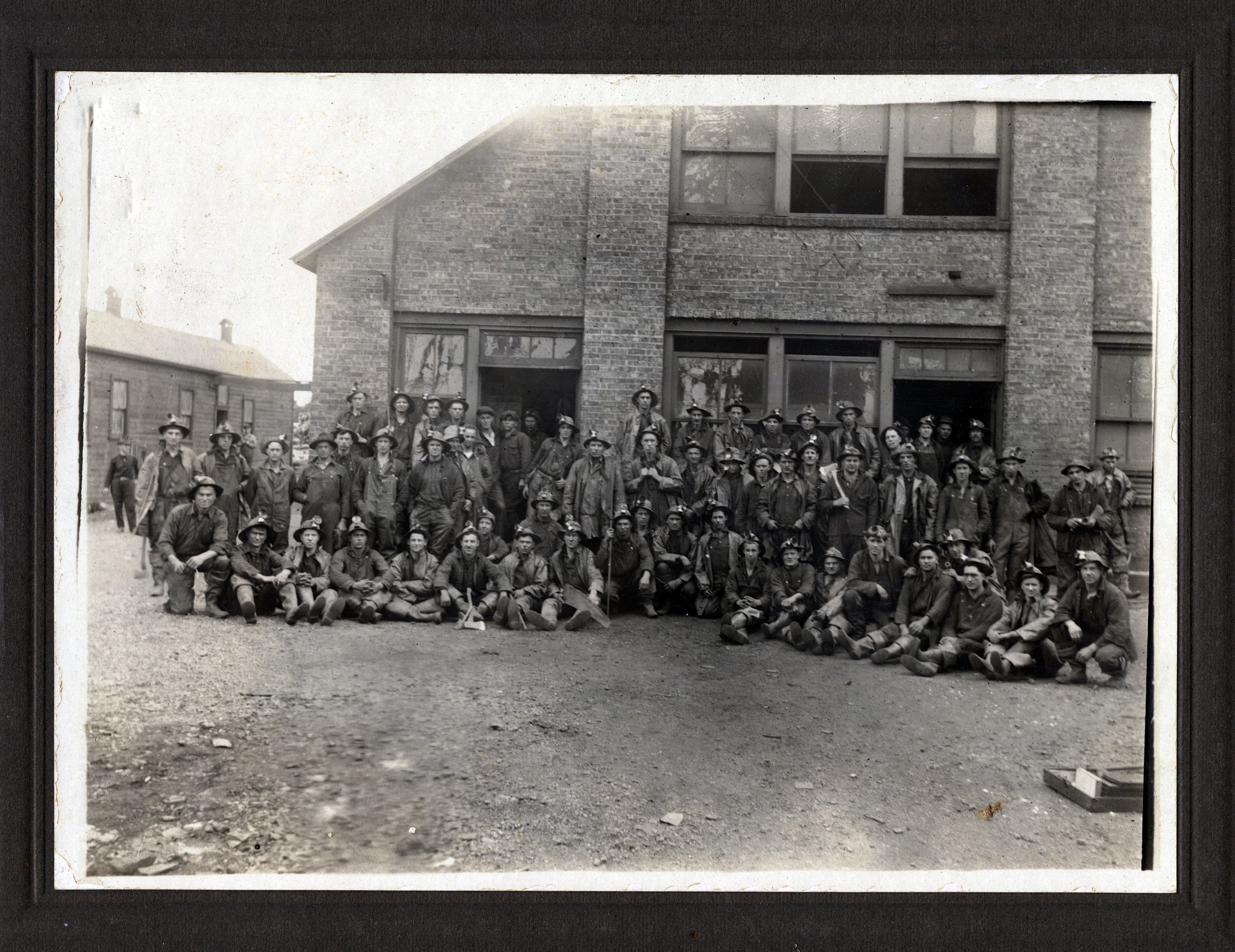 Men in mining gear in front of a brick building