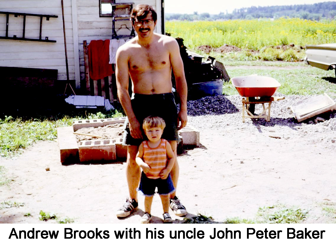 Little Andrew is standing in front of Pete. both are in front of a sand box,
     lined with cement blocks, and the front of the house.