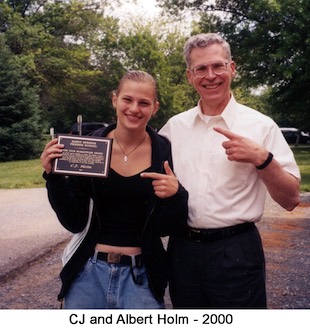 Standing in a parking lot, we are pointing at the award