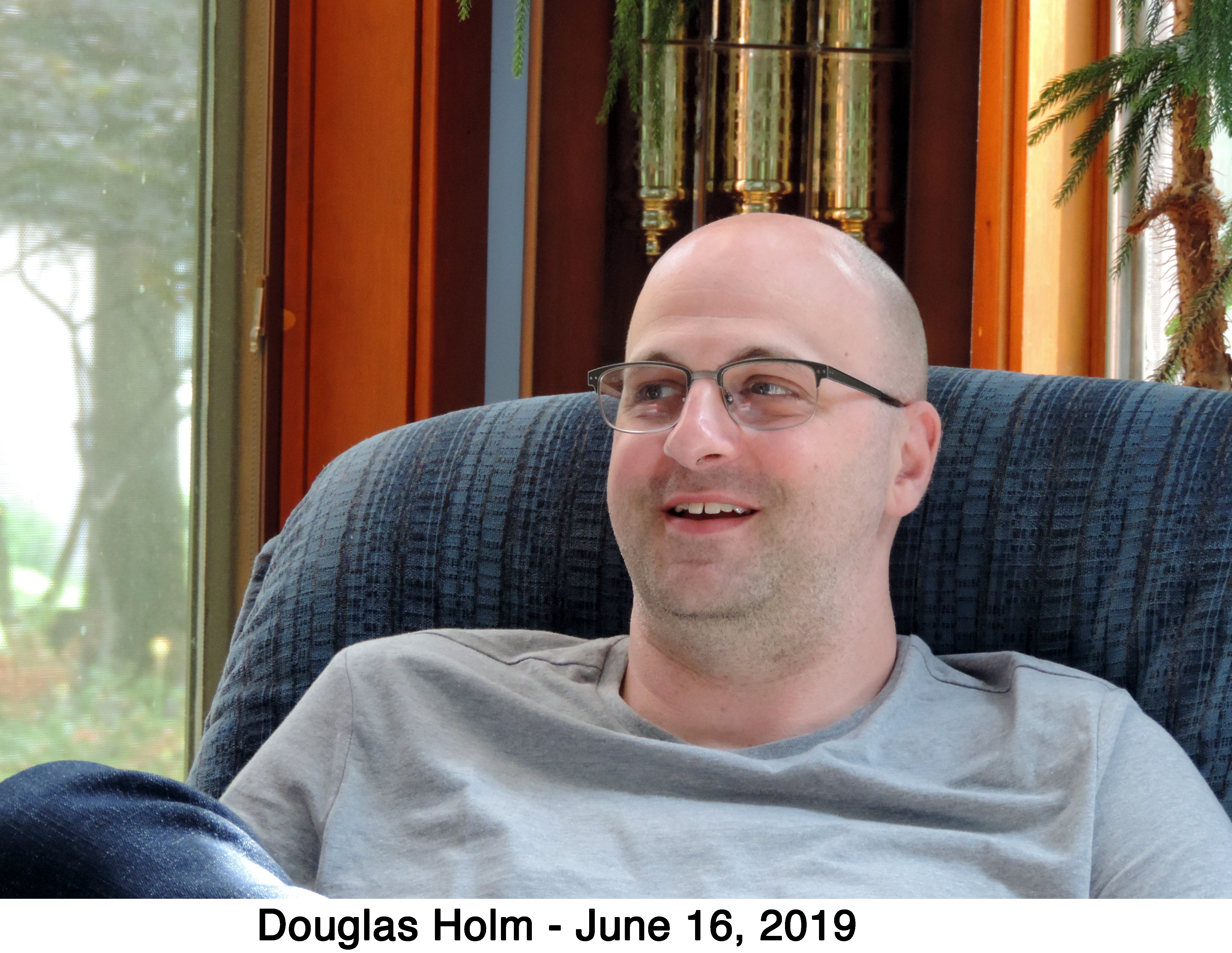 Douglas Holm smiling while sitting in a chair