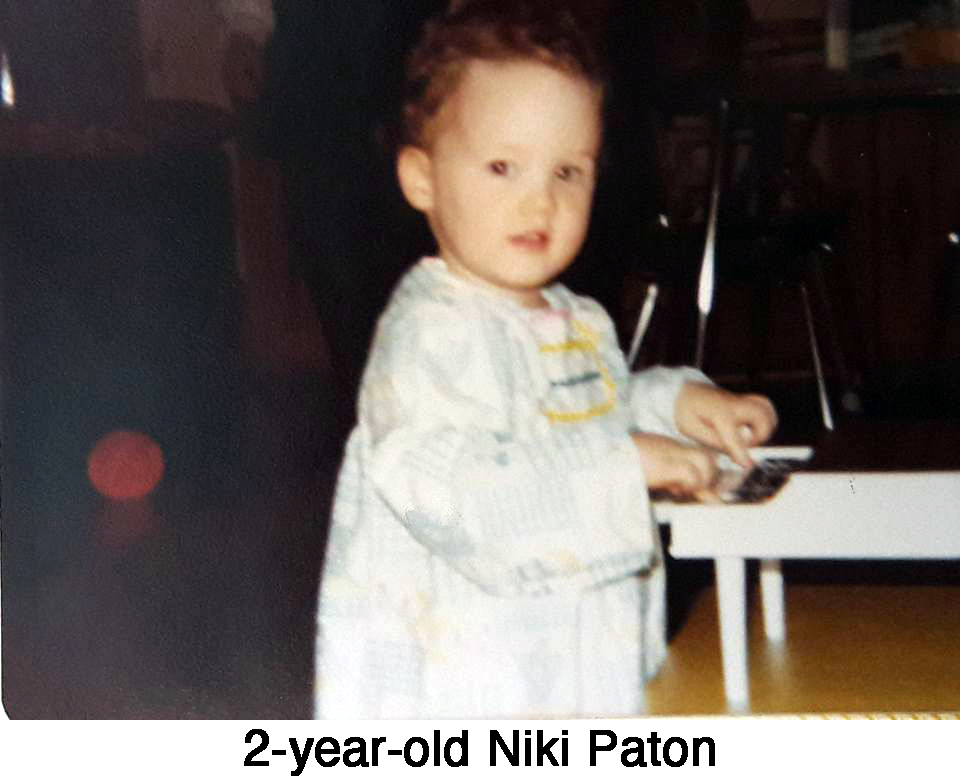 Little Niki is standing at a toy piano and looking at the camera