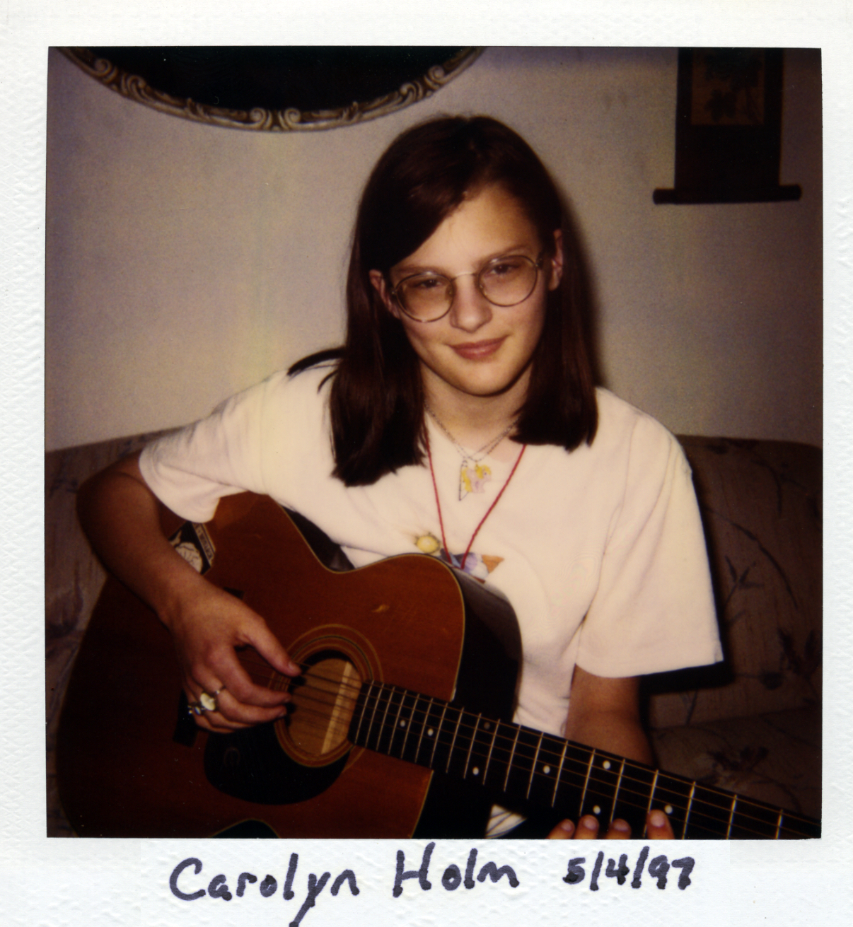 CJ Holm sitting on the sofa with her guitar