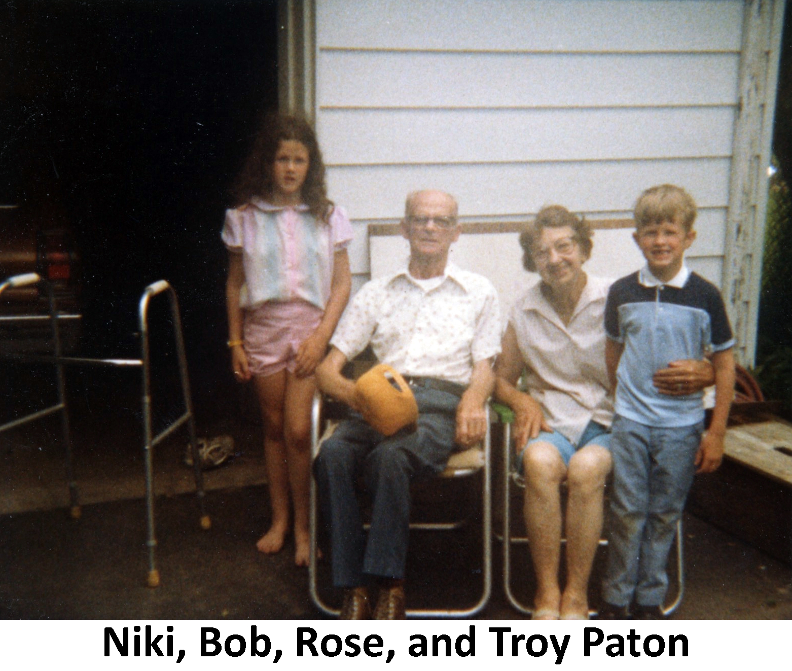 Bob and Rose Paton sitting on lawn chairs with their 
          grandchildren Niki and Troy Paton standing beside them
