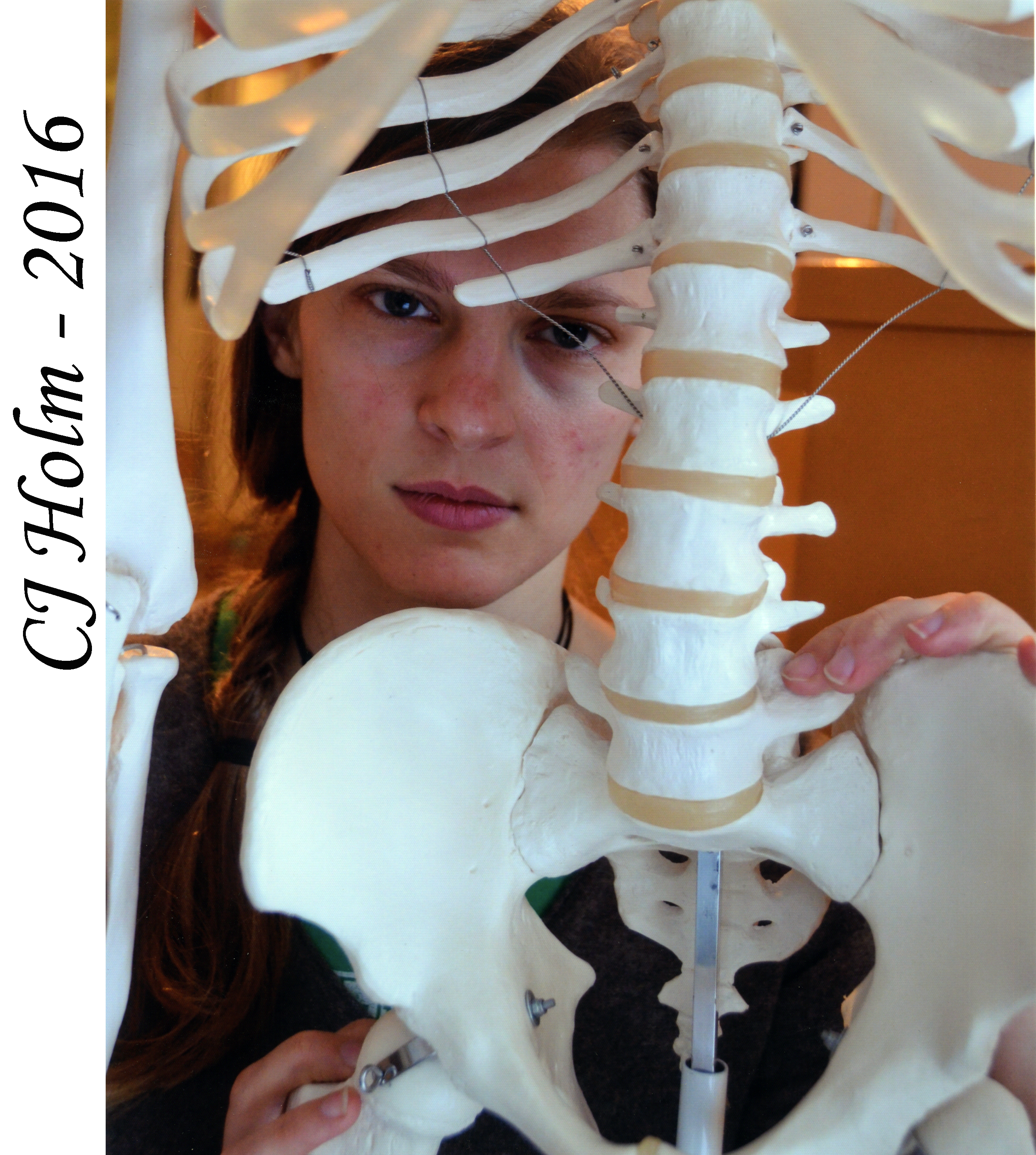She is looking at the camera through the midsection of a skeleton