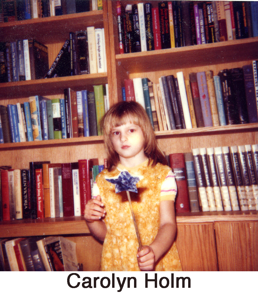 Carolyn Holm with a wand in front of bookcases