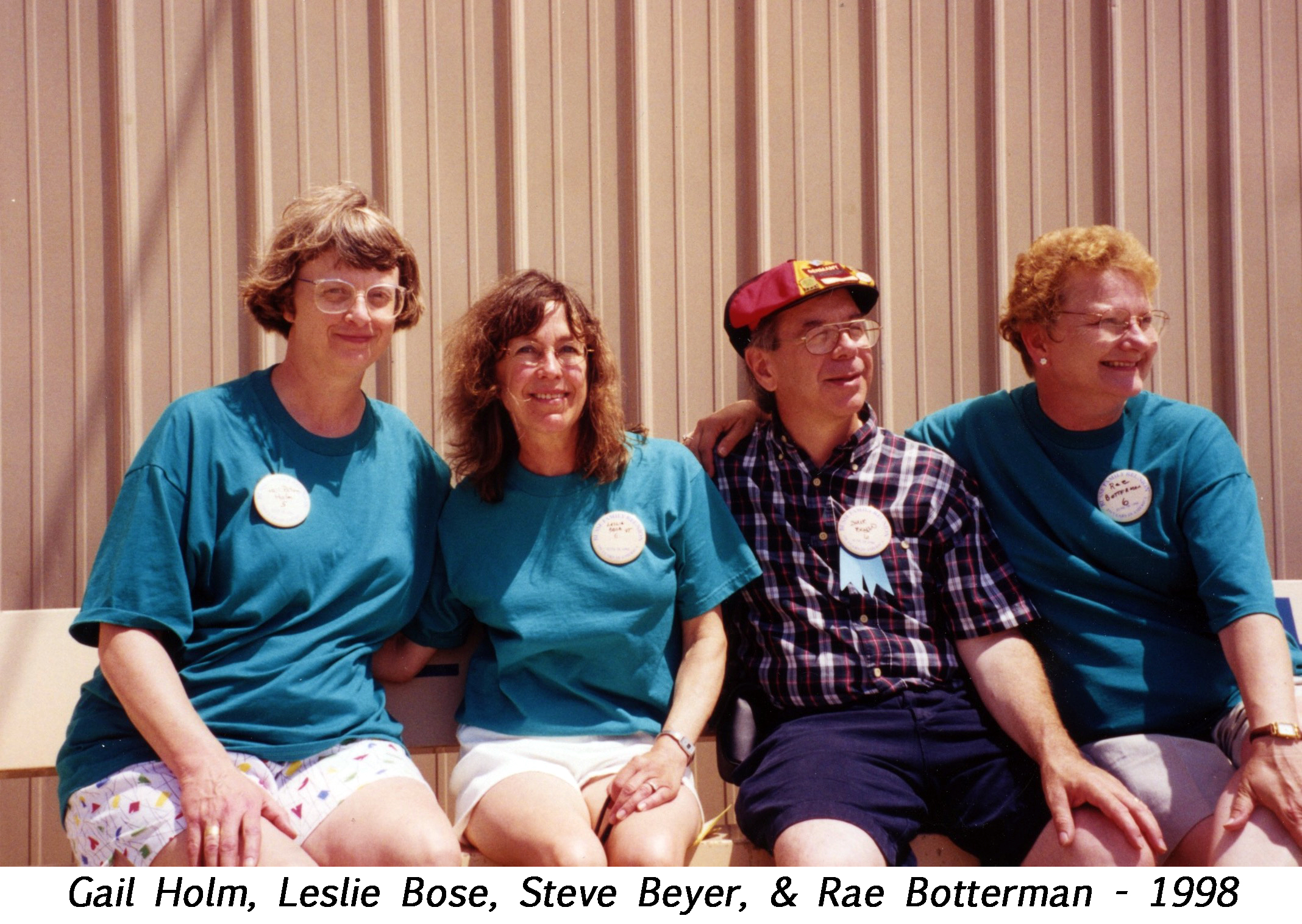 The four cousins are are seated side by side on a bench