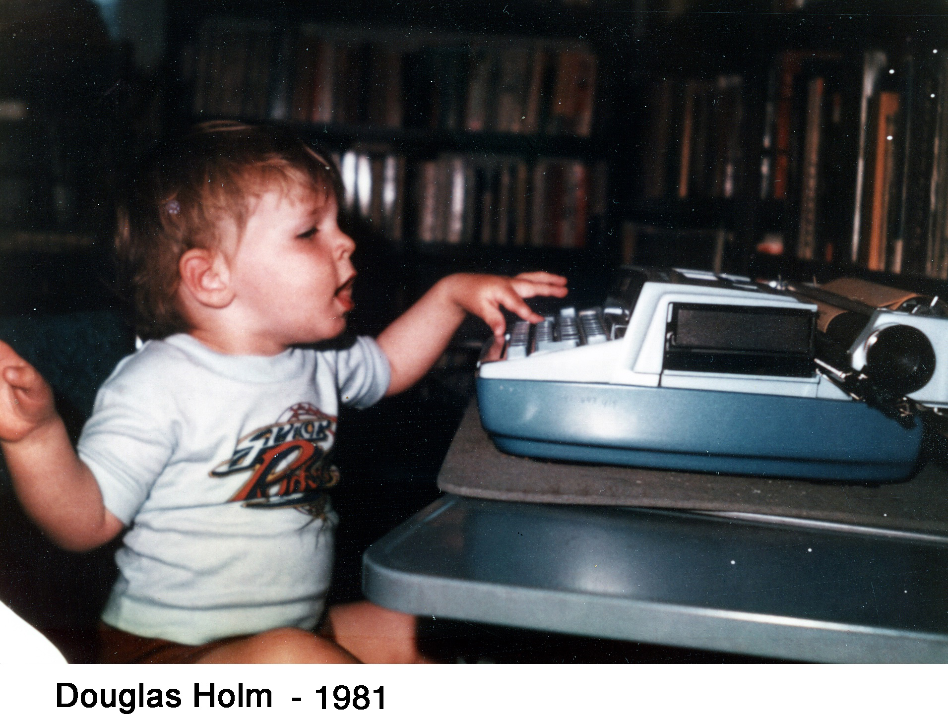 He is sitting in front of a typewriter and pressing keys with his left hand