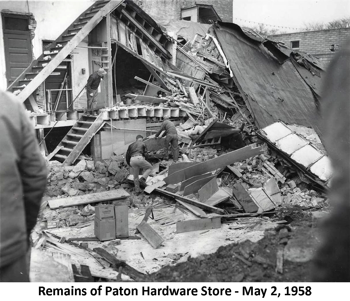 Debris in basement where Paton’s hardware store collapsed. 
          Two men are working in the hole.