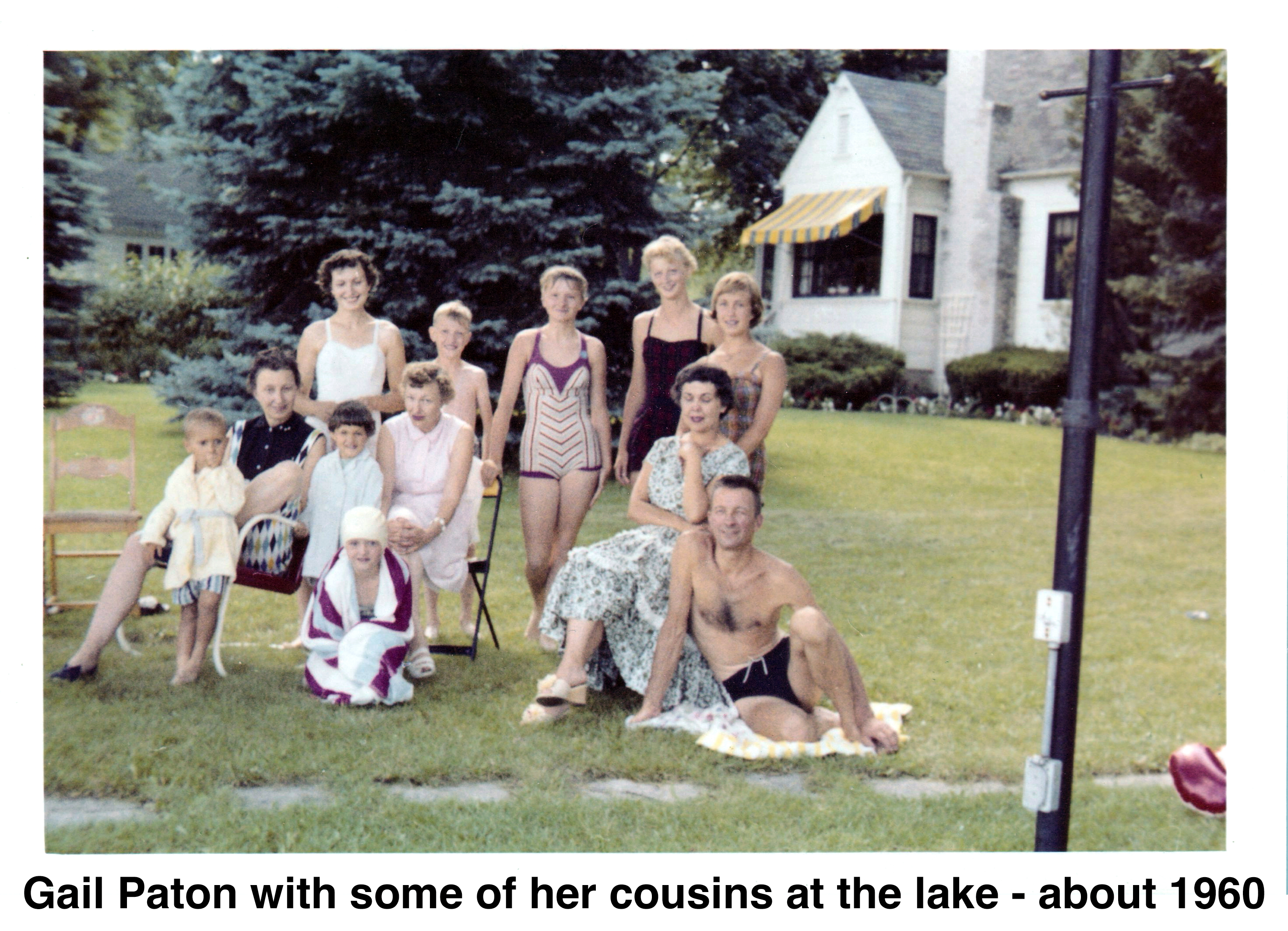 They are lined up for the photo on the grassy lawn. The younger 
             ones are weering bathing suits.