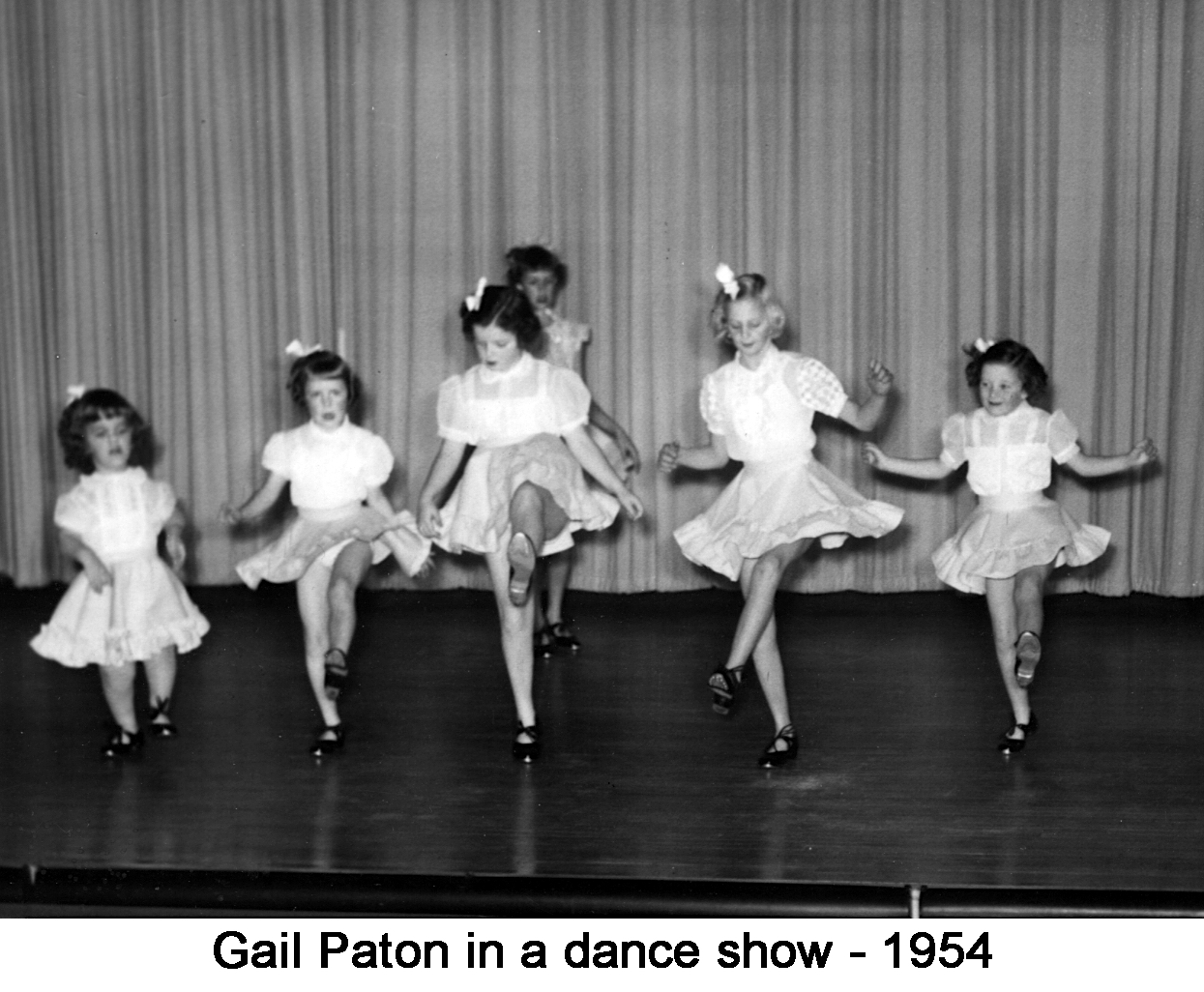 8-year-old Gail Paton kicking up a leg with other dancers on stage 