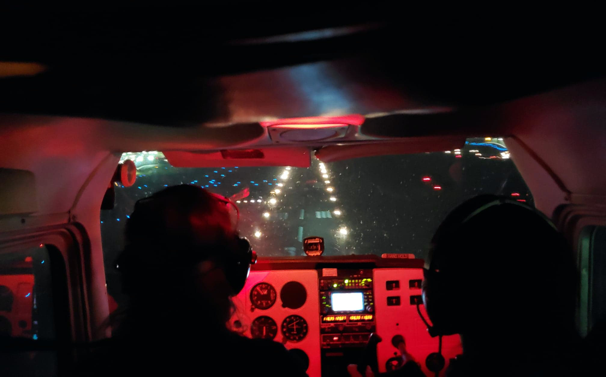 View from the cockpit toward the runway lights showing the instrument panel