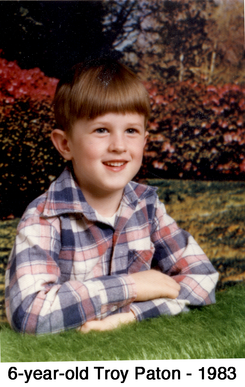 Troy Paton in a studio photo with a flowering shrub background