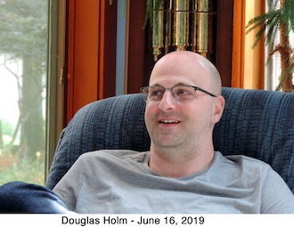 Douglas Holm smiling while sitting in a chair