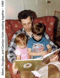 Carolyn, Albert, & Douglas Holm sitting in the arm chair and reading            a picture book