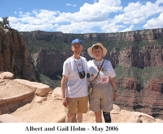 Gail and Al standing on the edge of a cliff with Grand Canyon cliffs 
           rising behind them