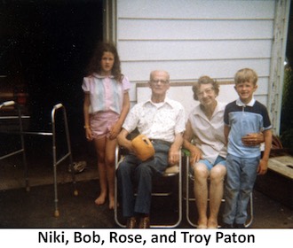 Bob and Rose Paton sitting on lawn chairs with their 
          grandchildren Niki and Troy Paton standing beside them