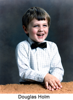 Douglas is laughing and wearing a bowtie in front of a dark background