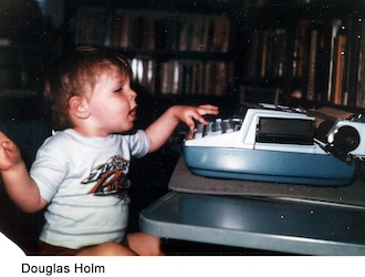 He is sitting in front of a typewriter and pressing keys with his left hand 