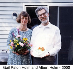 Gail Paton and Albert Holm celebrating their 25th anniversary           with flowers and a cake.