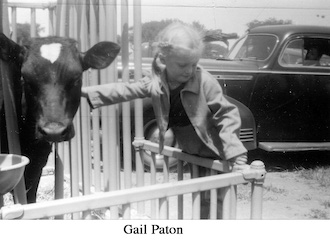 Gail Paton leaning on a fence and petting a calf