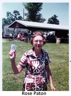 Rose Paton standing in Veterans Park and holding several pieces of paper,                possibly raffle tickets