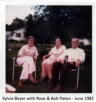 Sylvia Beyer, Rose Paton, and Bob Paton sitting on lawn chairs in the Paton’s
           side yard.