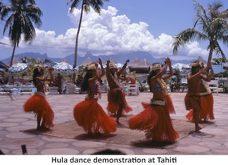 Six Tahitian women and two men in red skirts demonstrate a hula dance