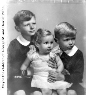 Three children in a studio photo, maybe from the 1930s. They are two        boys holding a girl. The oldest boy looks 9 or 10 and the girl looks about 2