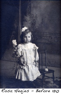Baby Rose Henjes holds a flower and has a bow in her hair for her portrait